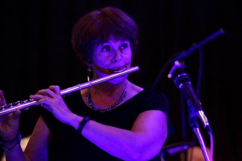 woman playing flute onstage in purple lights